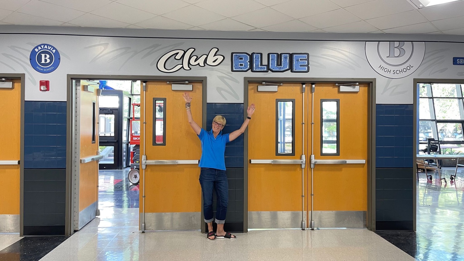 Club BLUE entrance mural with a staff member cheering in the doorway